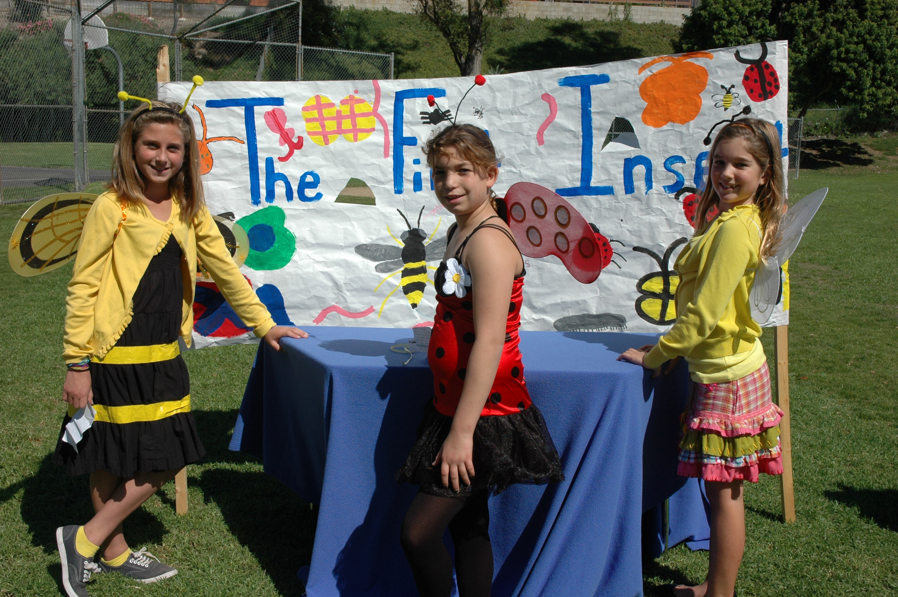 Students dressed as insects posing in front of their booth at our Earth's Timeline 